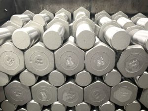 Stack of silver hexagonal headed bolts neatly arranged in rows